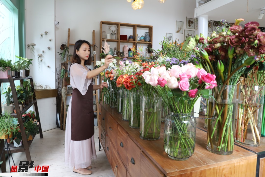 王黎媛是一名河南姑娘，在昆明念完大學(xué)后，就再也舍不下春城的藍(lán)天陽光、青山碧水，更舍不下這里的四時(shí)繁花，于是就干脆留了下來，成了一名媒體人。2017年的時(shí)候又毅然辭去工作，創(chuàng)業(yè)開起了花店，成了都市里的一名“花房姑娘”。圖為王黎媛在自己的花店中整理鮮花。新華網(wǎng) 周亞平/攝 念新洪/文